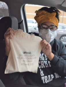 a woman holds up a complimentary tote bag with the UTHSC logo
