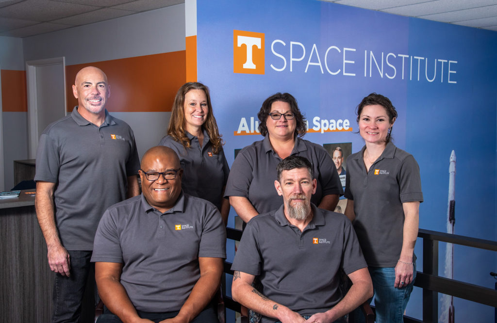 A group of six UT space institute employees in matching polo shirts
